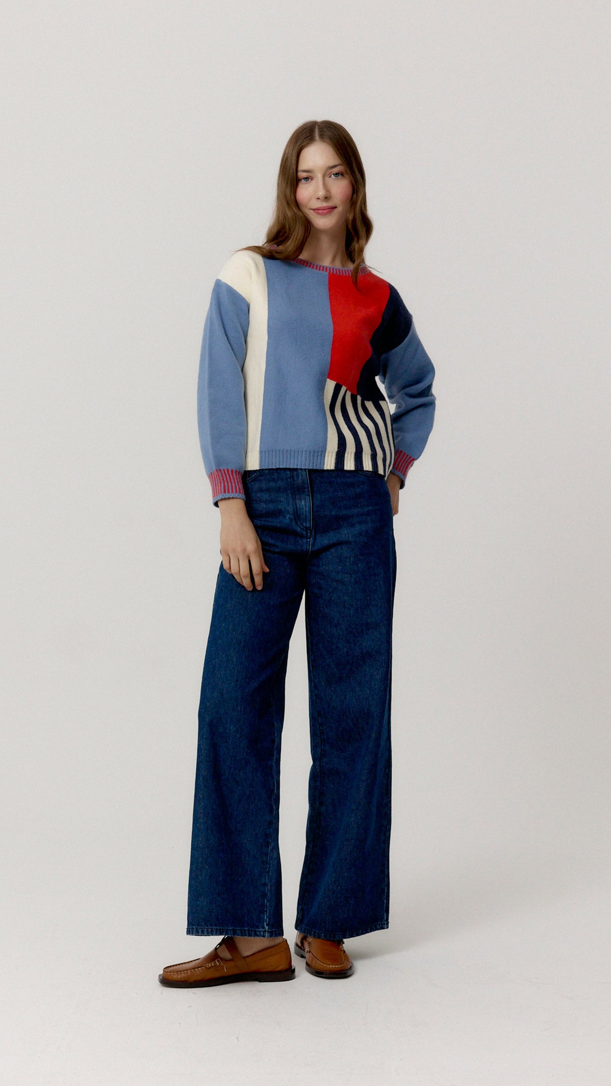 Jersey Pop azul, rojo, crudo y marino con vaqueros y mocasines, vista frontal.