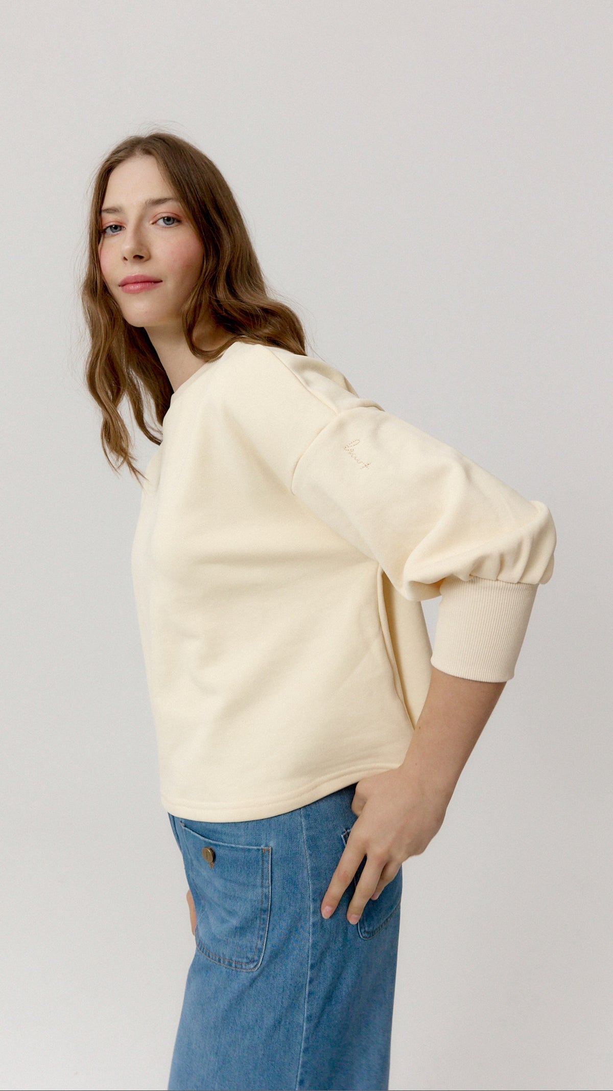Sudadera Musseta crema de perfil, con manga amplia y puño elástico.
