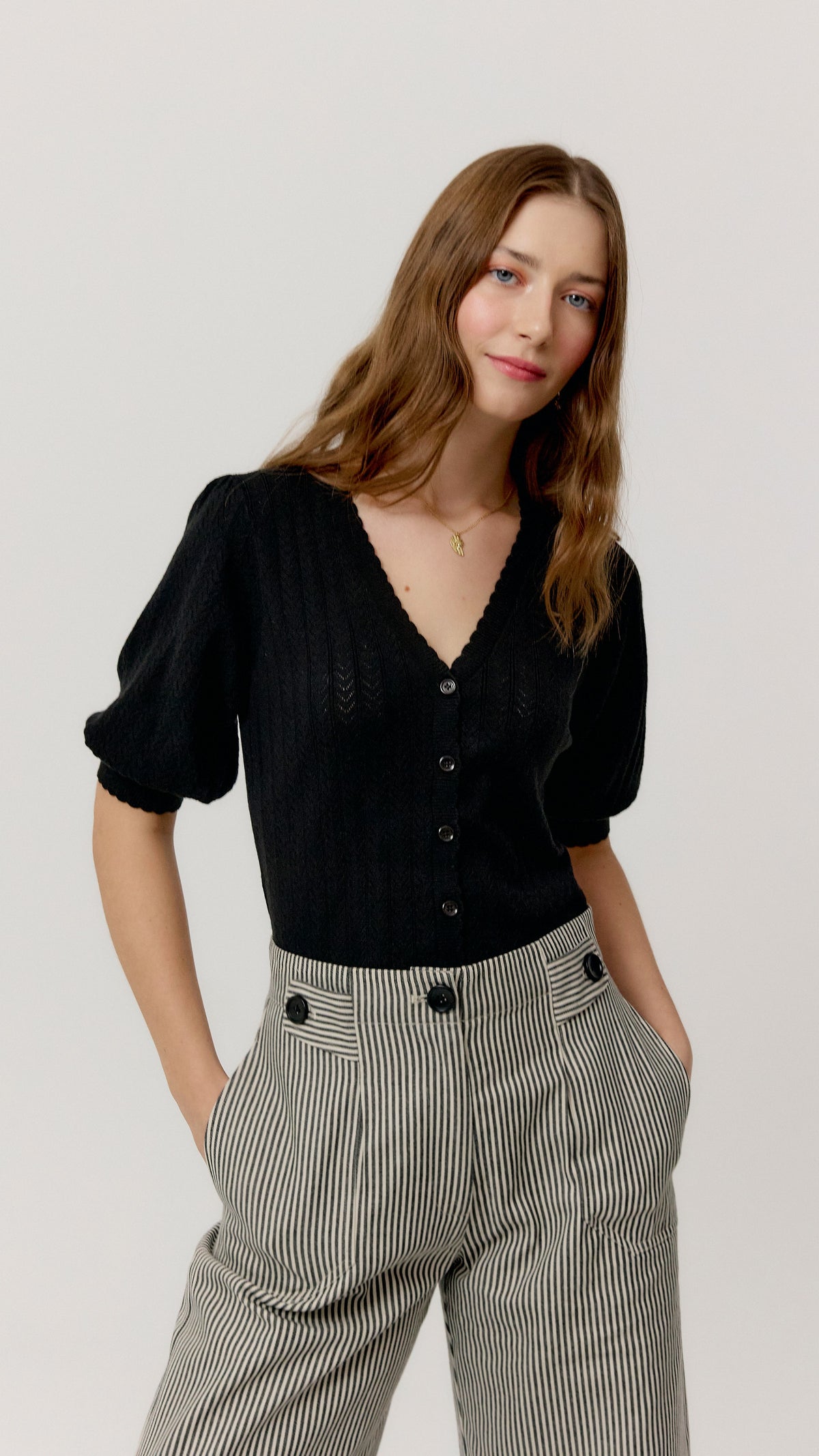 Top Ada negro de punto calado combinado con pantalón de rayas, vista de tres cuartos.