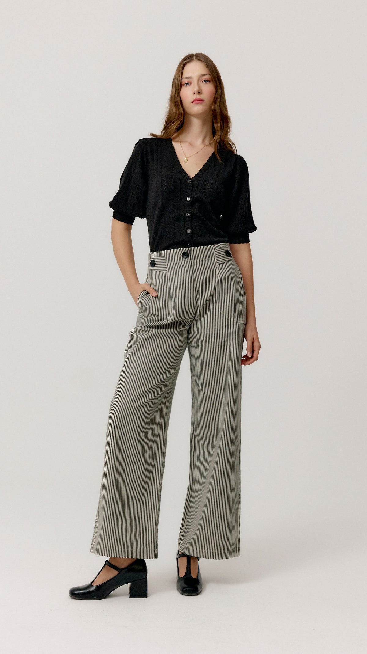 Look con top Ada negro, pantalón ancho de rayas y zapatos negros.