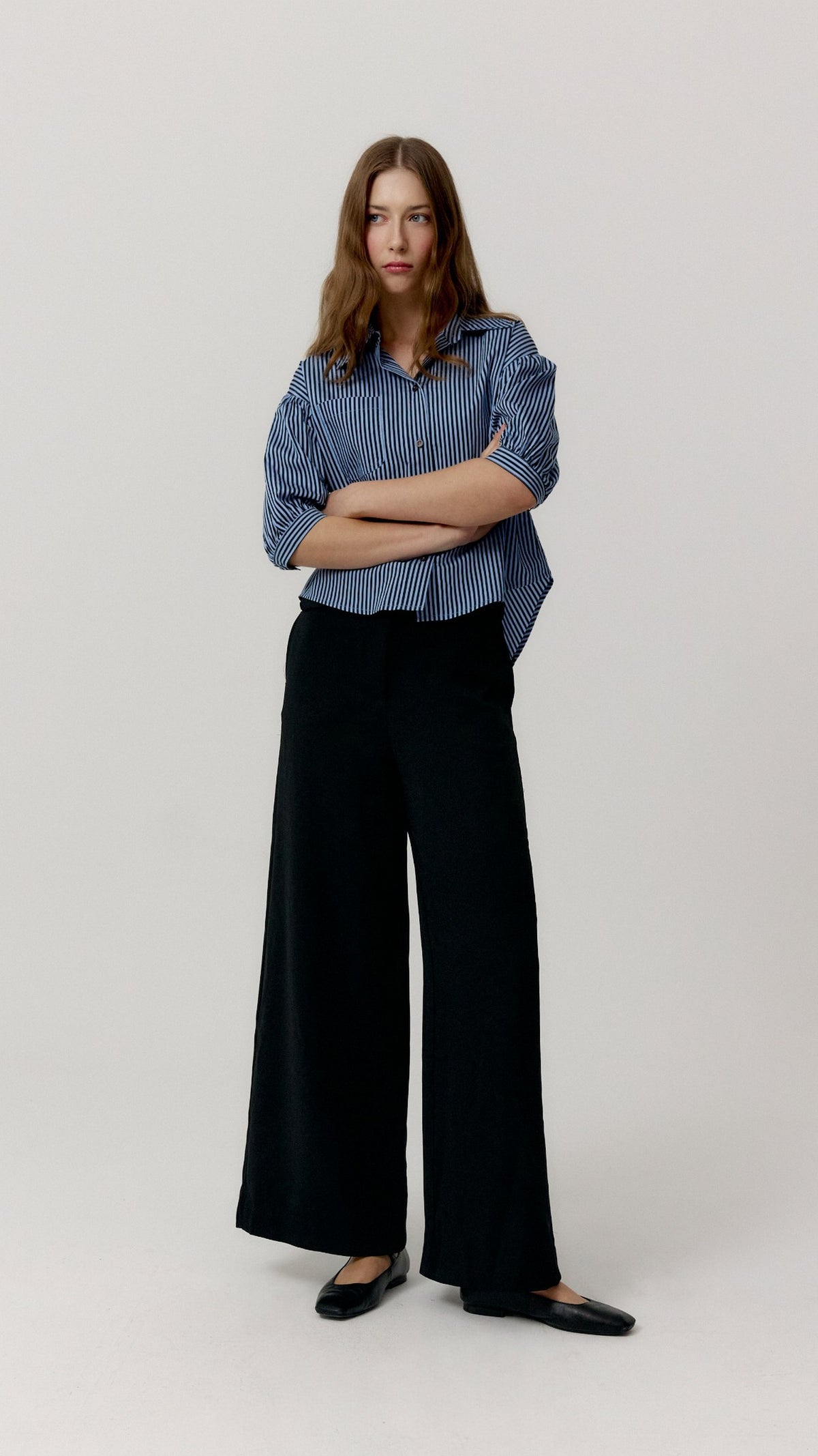 Pantalón Edmond negro de Biscuit en look frontal con camisa azul de rayas
